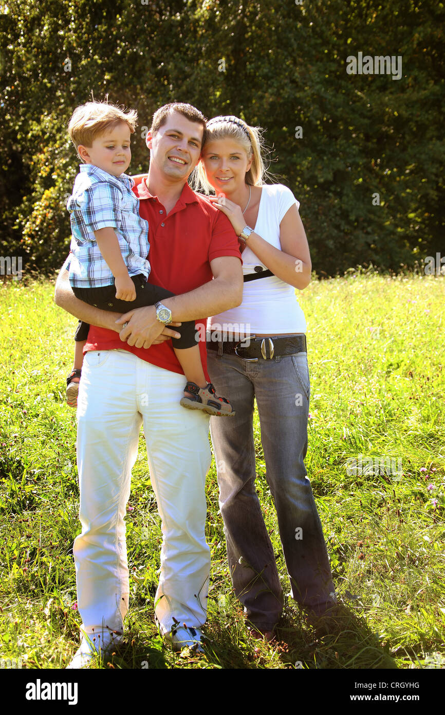 junge Familie stehen auf einer Wiese im Sommer. Vater mit