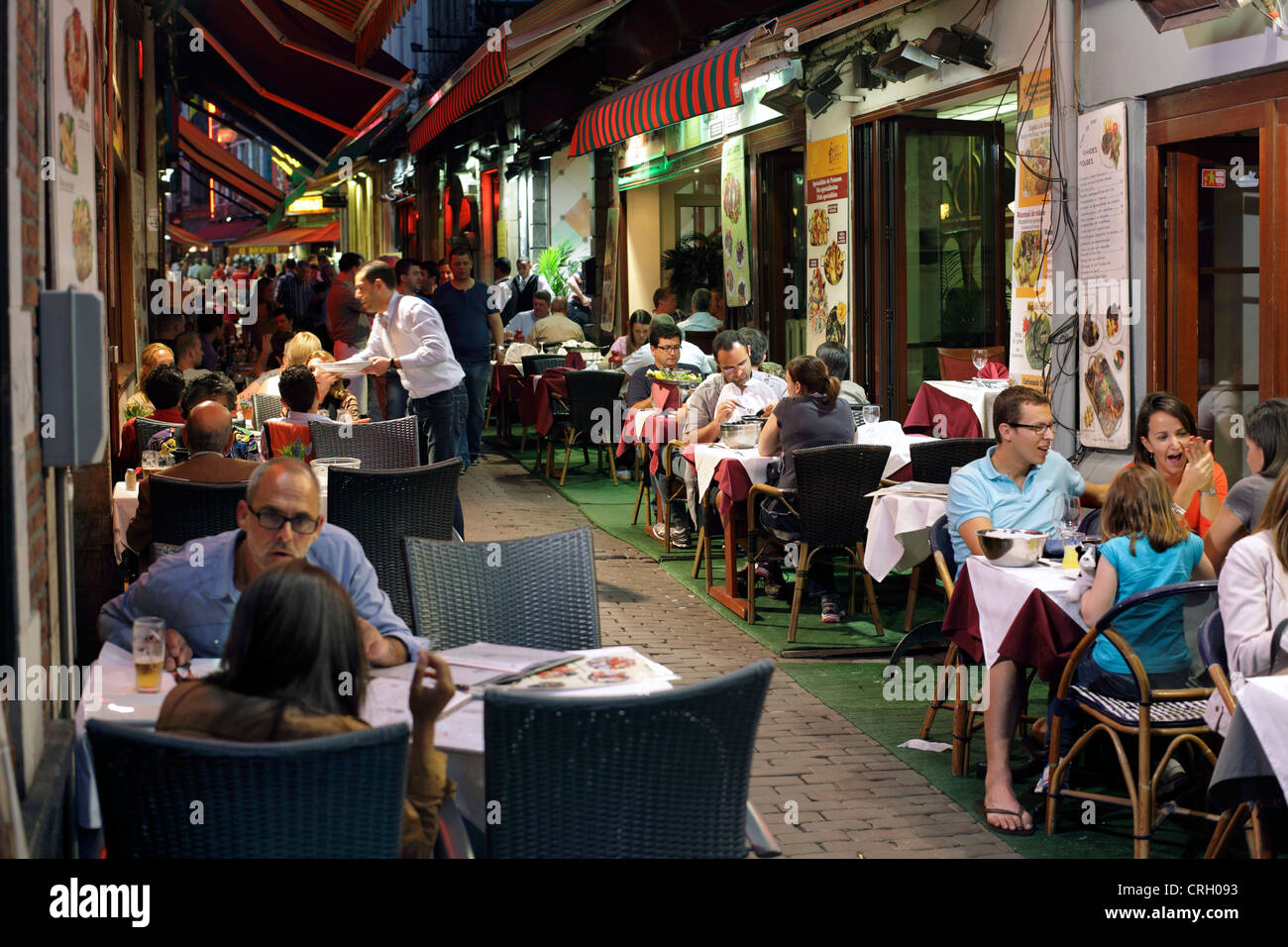 Essen im Freien auf der Rue des Bouchers, Unterstadt, Brüssel, Belgien. (Am späten Abend geschossen - Foto nach Einbruch der Dunkelheit.) Stockfoto