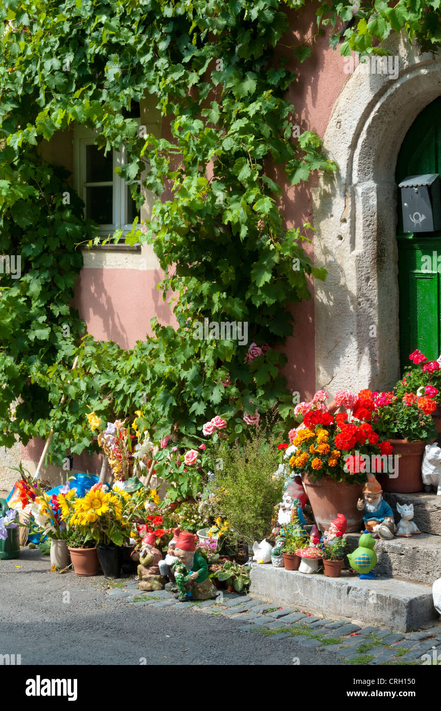 Blumen, Topfpflanzen und Gartenzwerge vor einem Haus in einem Dorf in Deutschland Stockfoto