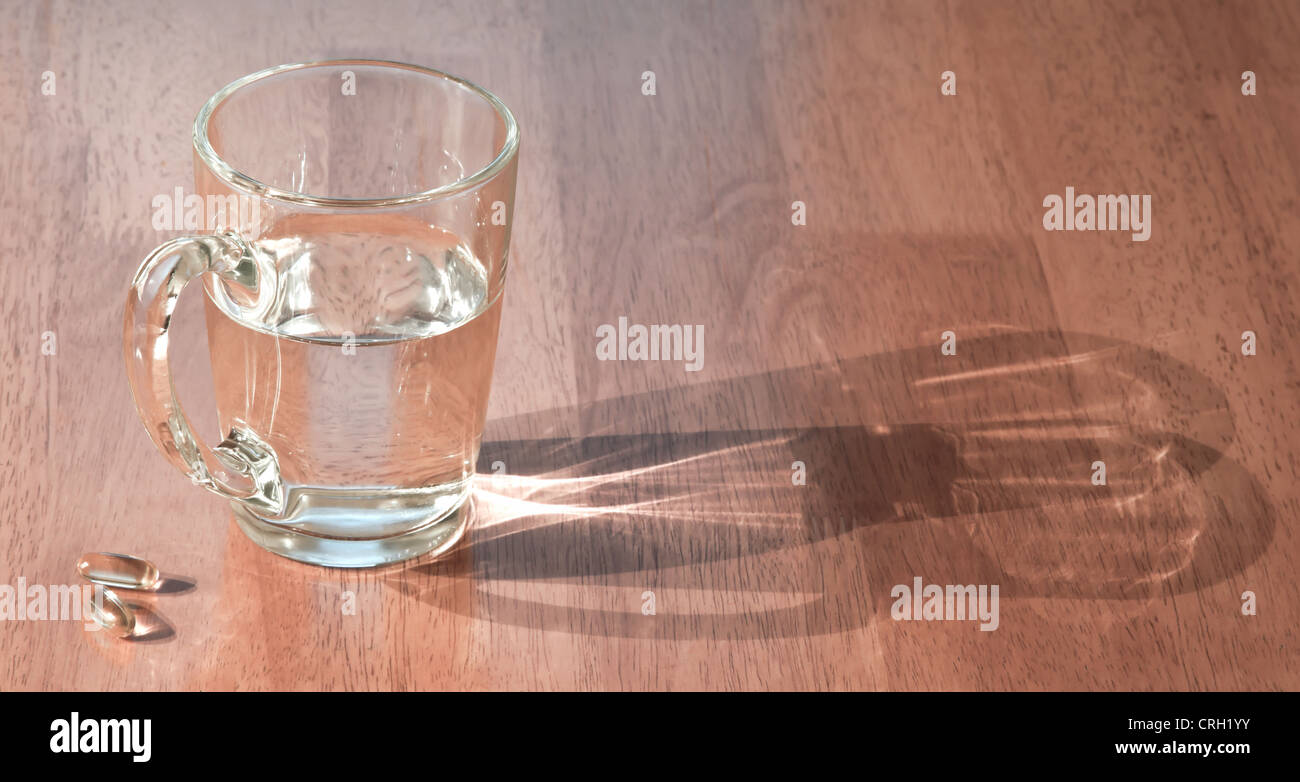 Tasse Wasser mit Pillen auf Holztisch Stockfoto