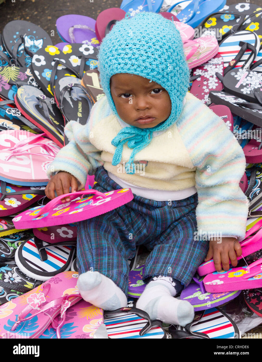 Baby spielt mit Kunststoff-Sandalen auf Stall, Markt Analakely, Antananarivo, Madagaskar Stockfoto