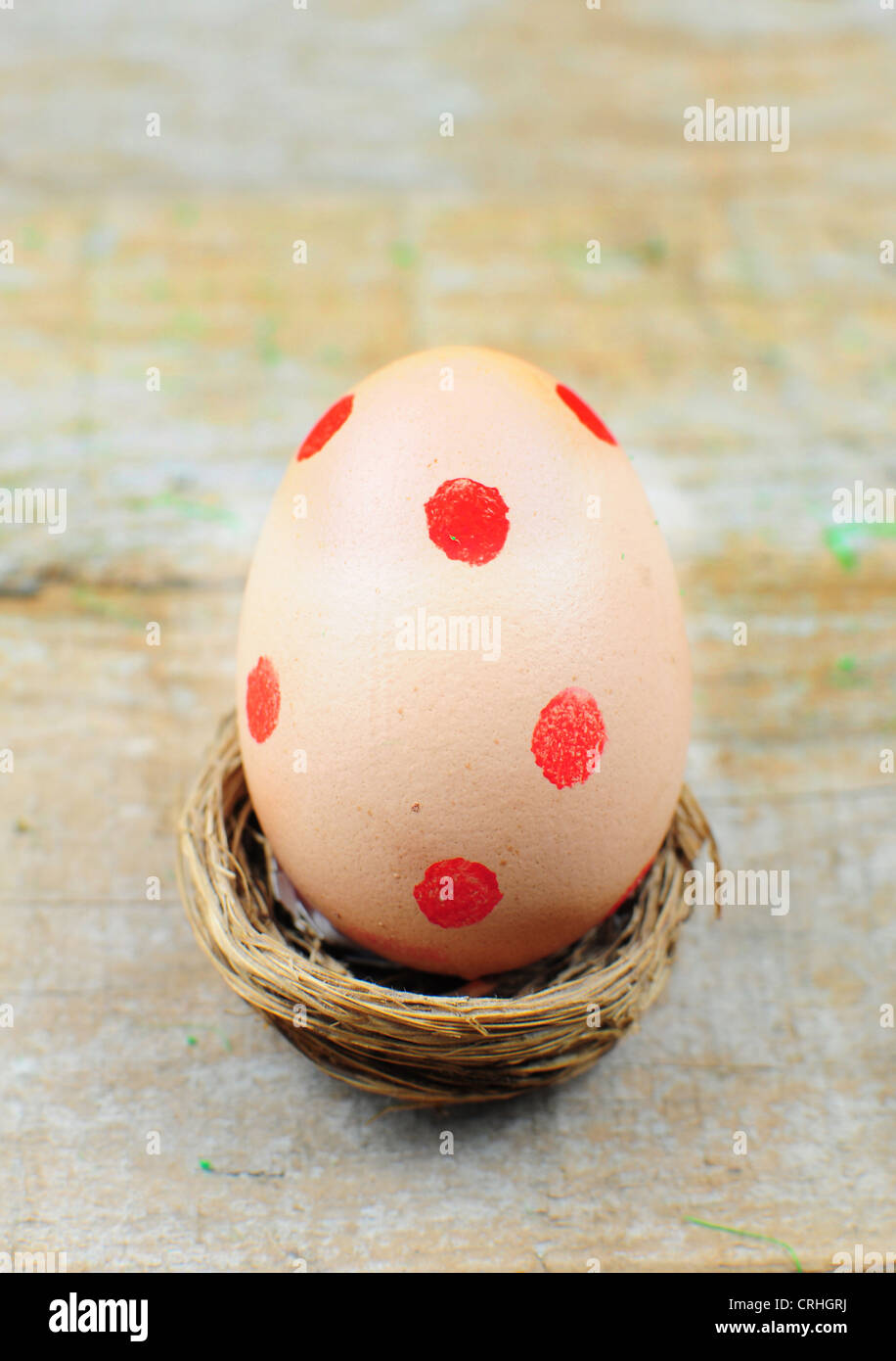 Osterei mit roten Punkten im Nest auf hölzernen Hintergrund Stockfoto