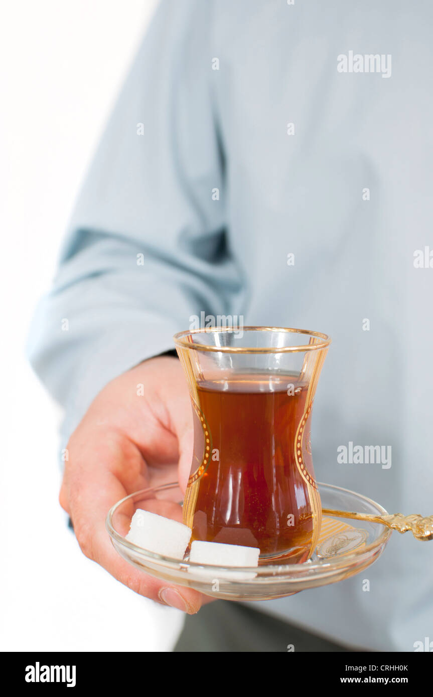Des jungen Mannes Hand serviert traditionelle türkische Chai in Glas Stockfoto