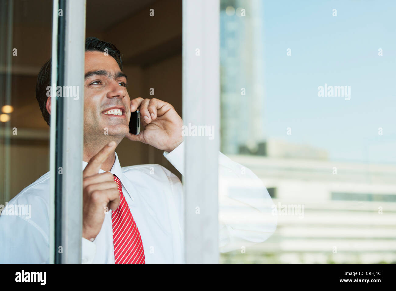 Geschäftsmann mit Handy im Büro von außerhalb Fenster gesehen Stockfoto