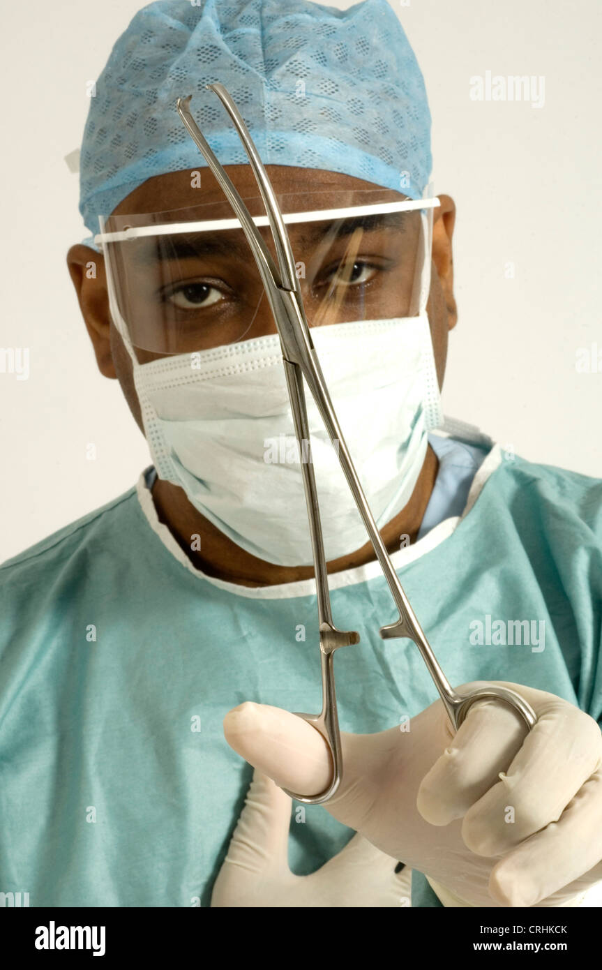 Ein Chirurg, gekleidet in Schutzkleidung mit ein paar Zangen Stockfoto
