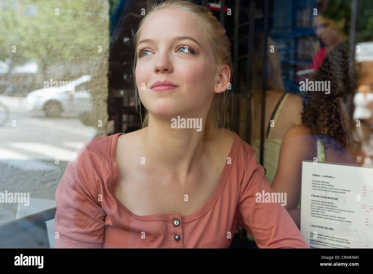 Junge Frau am Straßencafé, nachschlagen und lächelnd Stockfoto