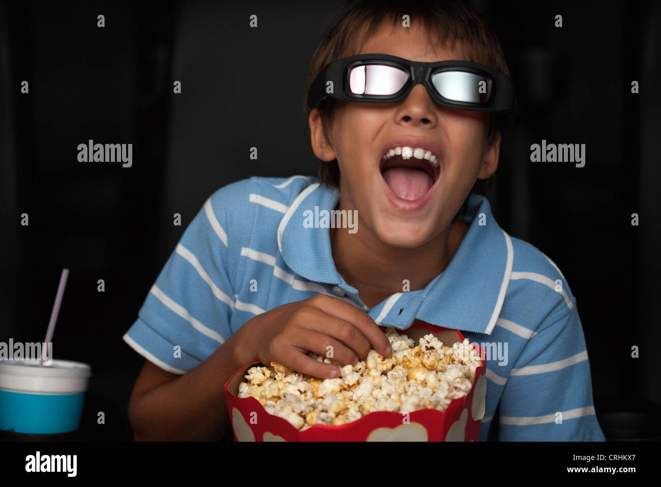 Junge, lachen und Essen Popcorn in 3-d-Film im theater Stockfoto