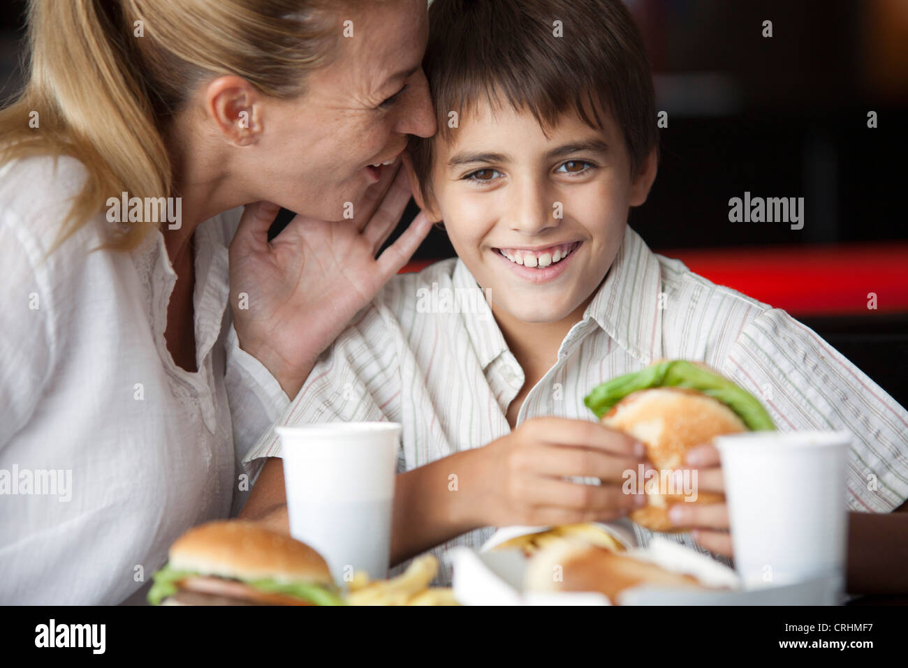 Mutter Sohn das Ohr im Fastfood-Restaurant zu flüstern Stockfoto