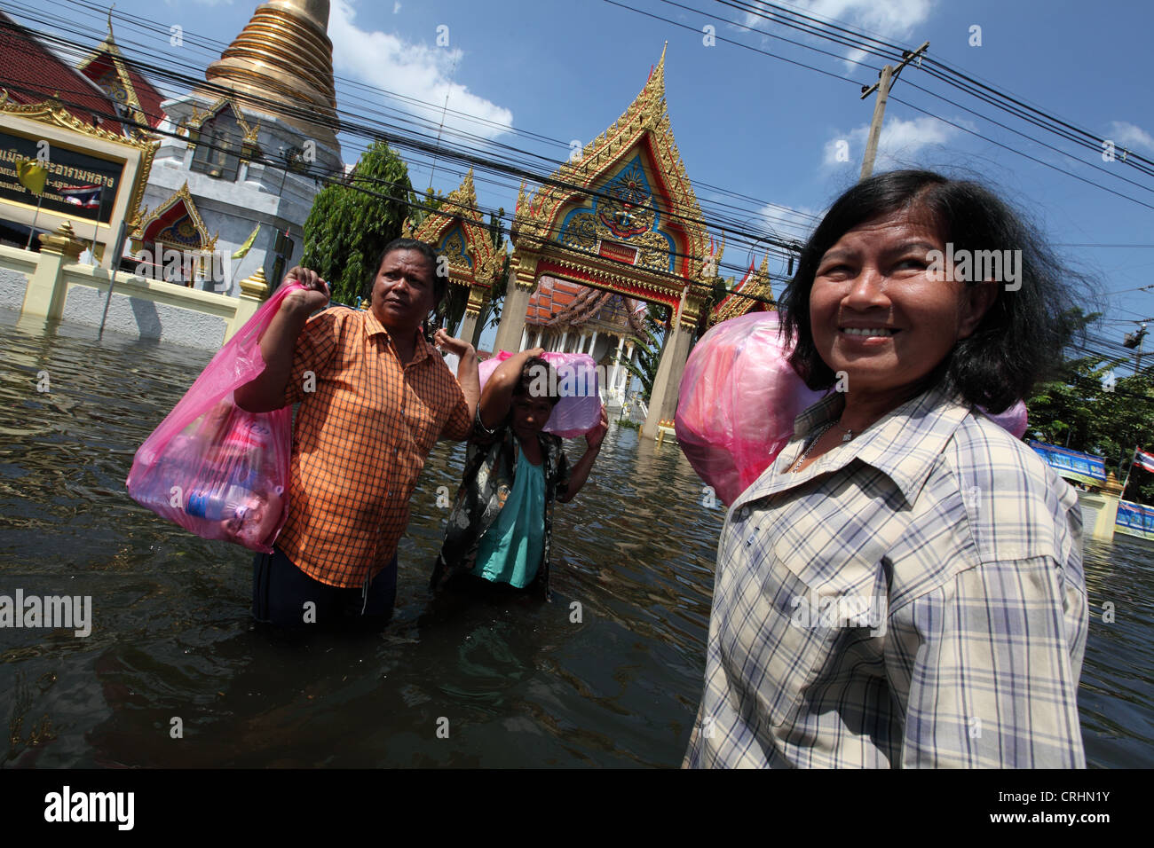 Frauen tragen Rationen von Nahrung und Wasser, wie Überschwemmungen Bereich Don Muang in Bangkok zu verwüsten. Stockfoto