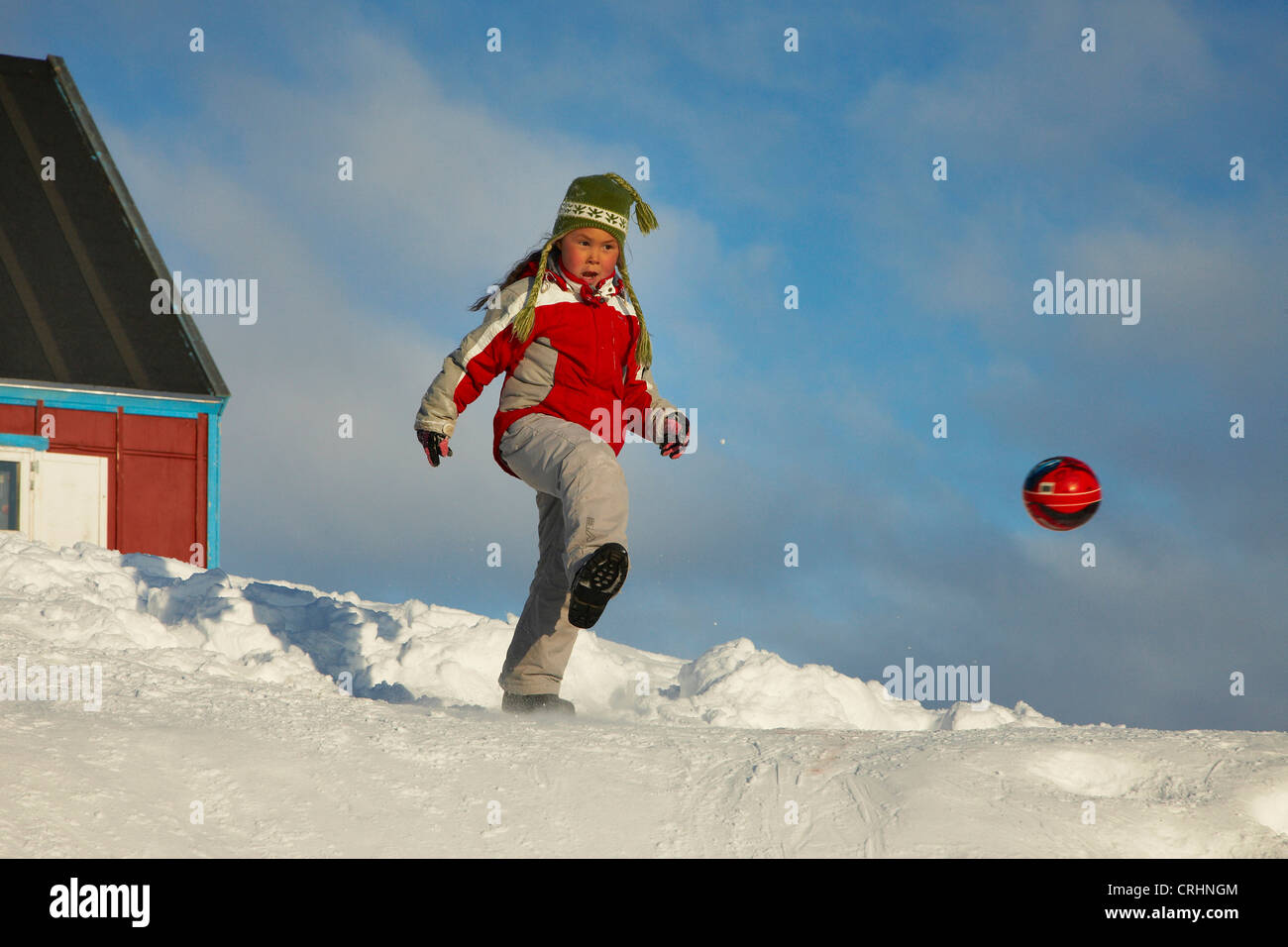 Mädchen mit Ball im Schnee, Grönland, Ostgroenland, Tunu, Kalaallit Nunaat, Scoresbysund, Kangertittivag, Ittoqqortoormiit Stockfoto