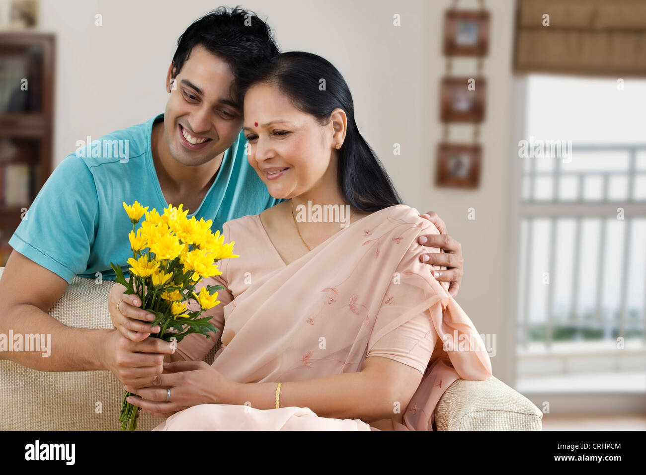 junger Mann verschenken Blumenstrauß an seine Mutter Stockfoto