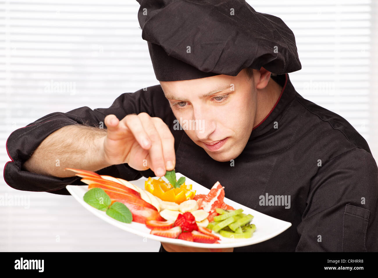 Koch in schwarzer Uniform dekorieren leckere Obstteller Stockfoto