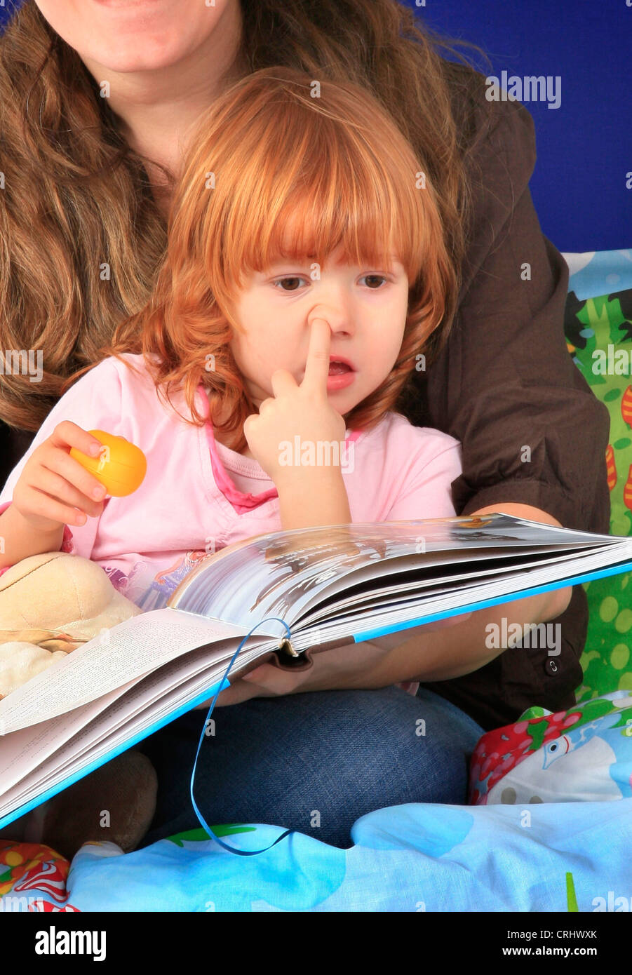Kleine rothaarige Mädchen eine Gutenachtgeschichte sammeln ihre Nase anhören Stockfoto
