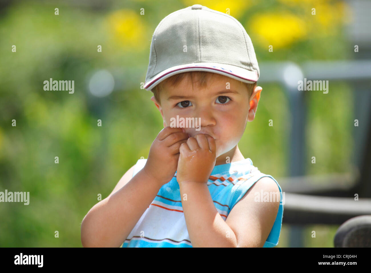 kleiner Junge mit Schirmmütze kauen ein Bonbon Stockfoto