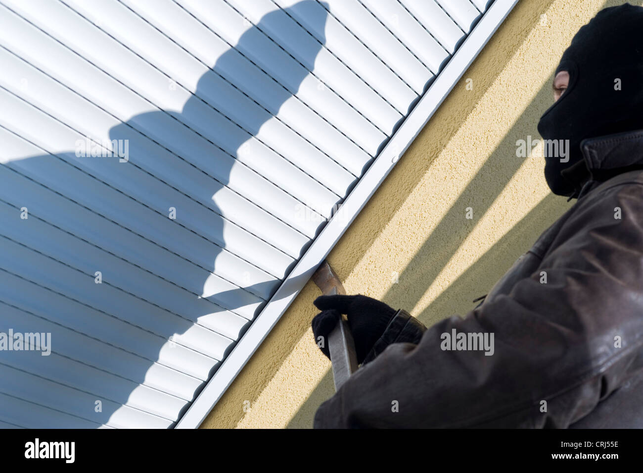 Housebreaker durch die Hintertür, Einreiten vor geschlossenen jalousie Stockfoto