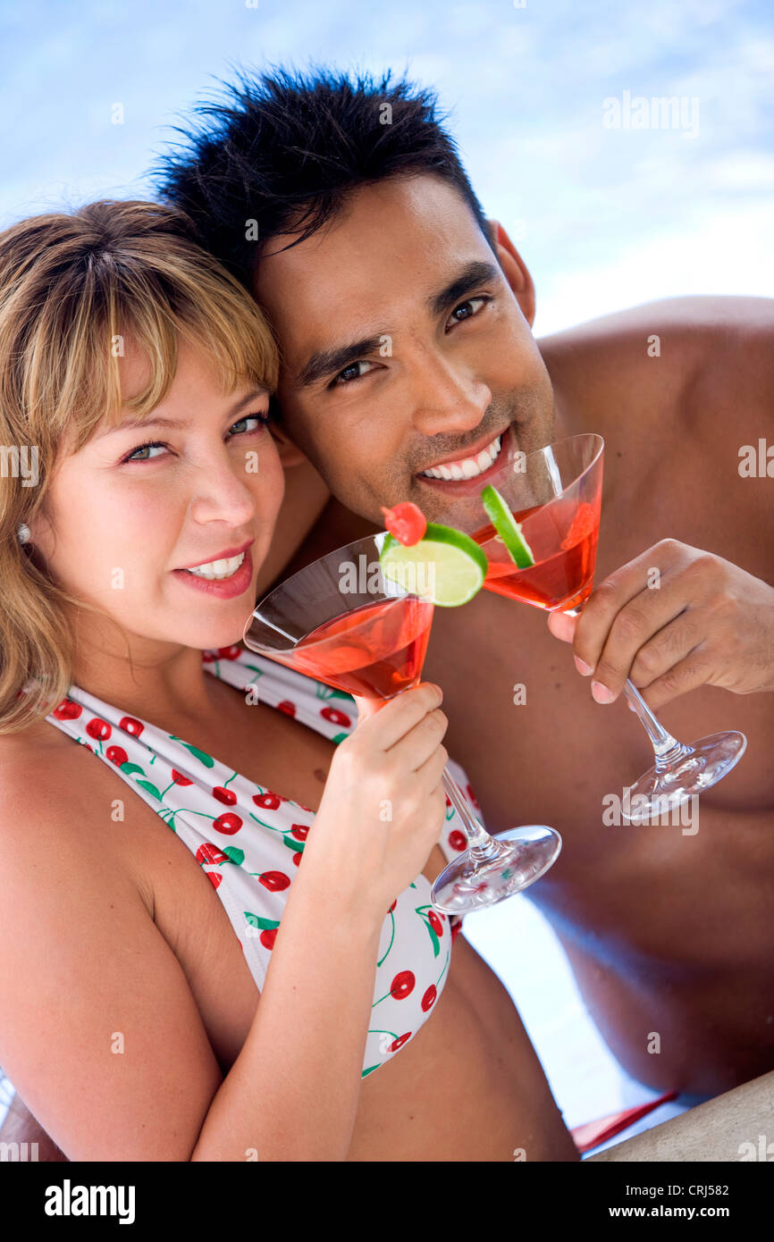 glückliches junges Paar relaxen am Pool, Cocktails genießen Stockfoto