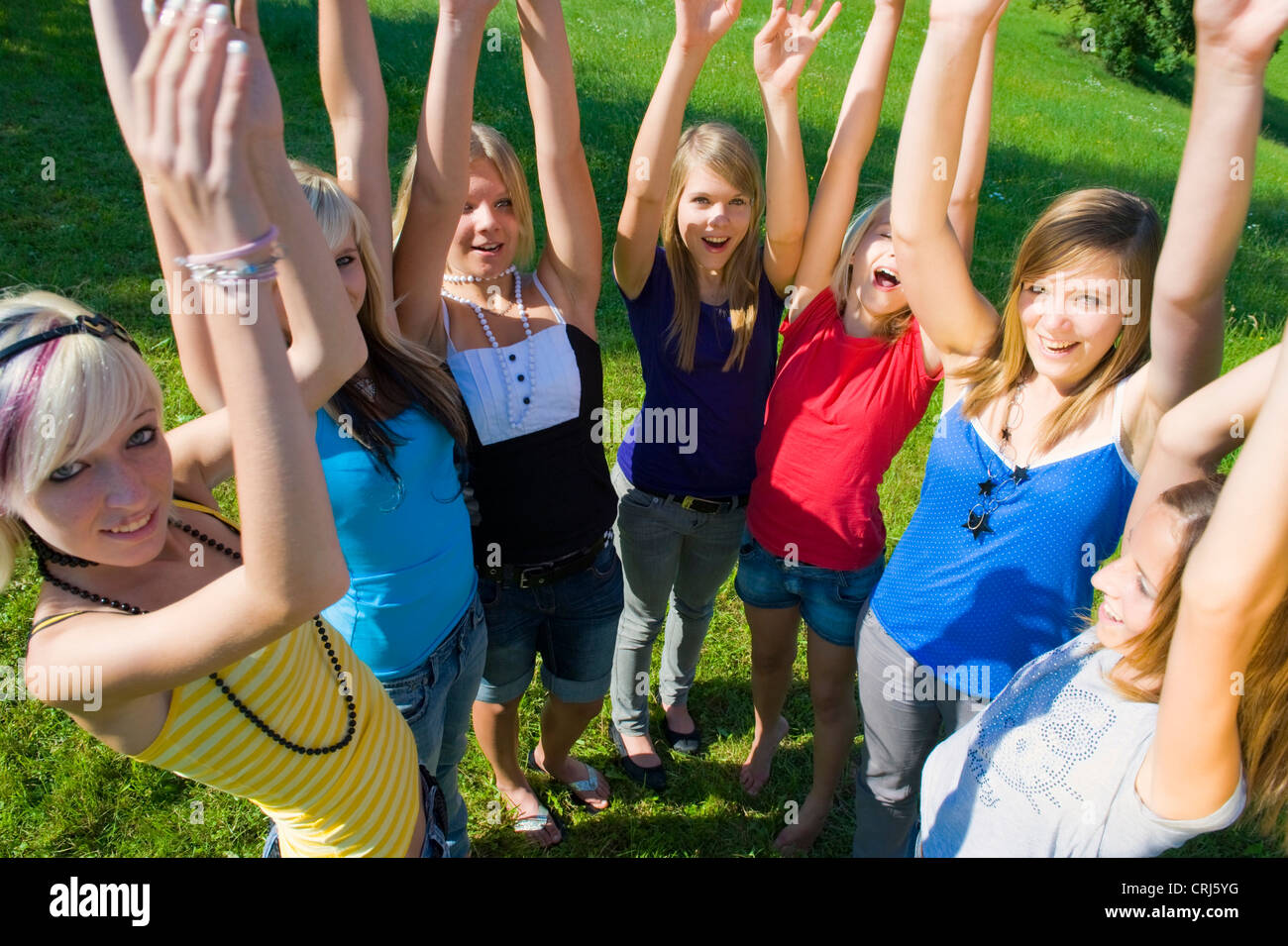sieben Mädchen im Teenageralter stehen im Halbkreis warfen ihre Arme in die Luft mit asmile Stockfoto