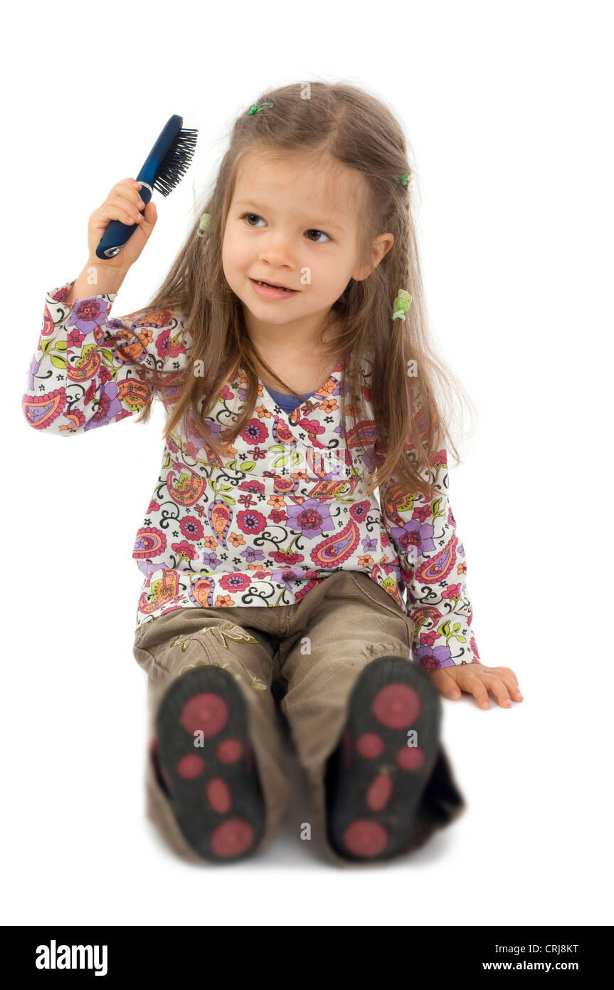 kleines Mädchen sitzt auf dem Boden mit einer Haarbürste Kämmen Stockfoto