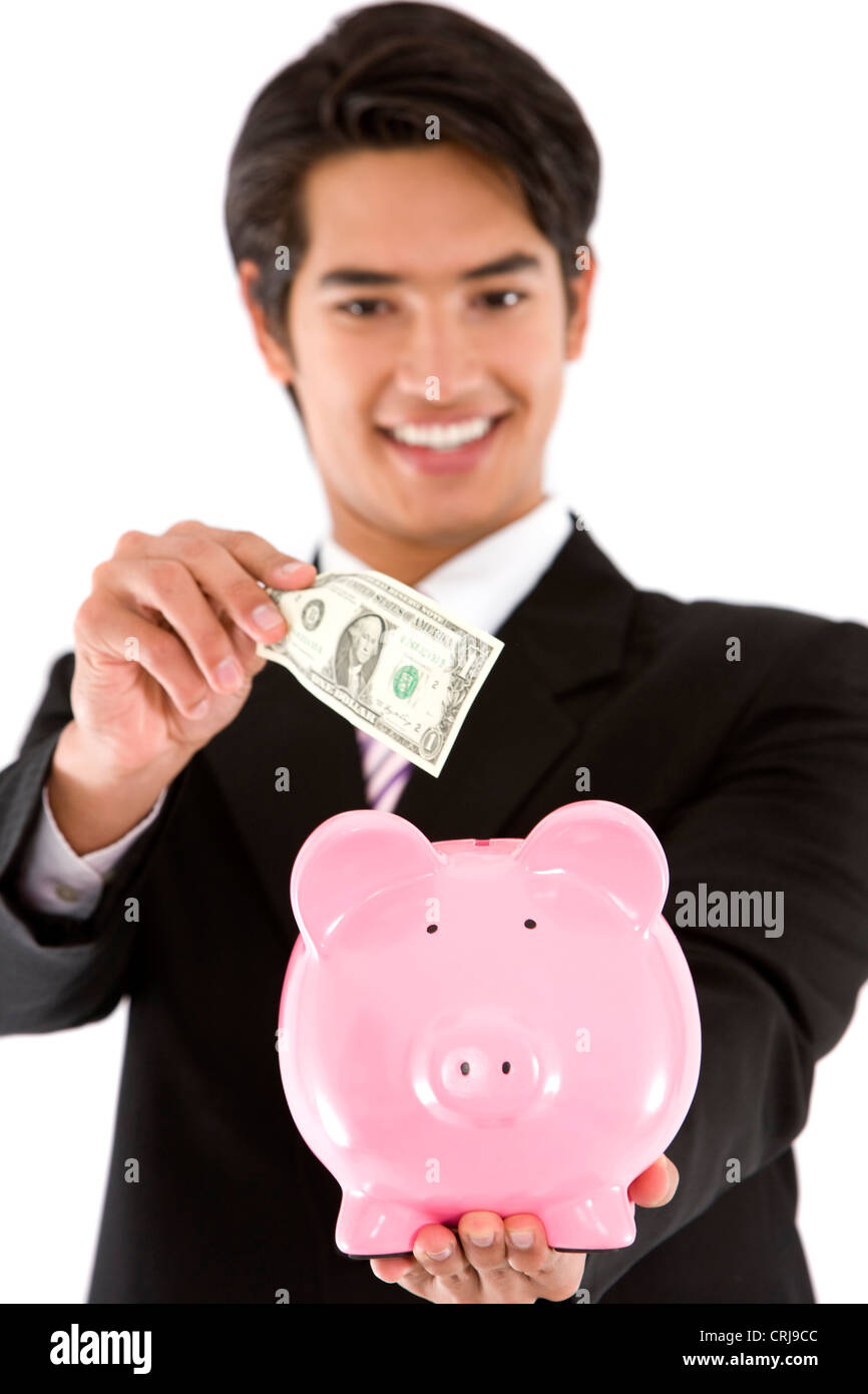 Jungunternehmer setzen eine Rechnung in seinem Sparschwein mit einem Lächeln Stockfoto