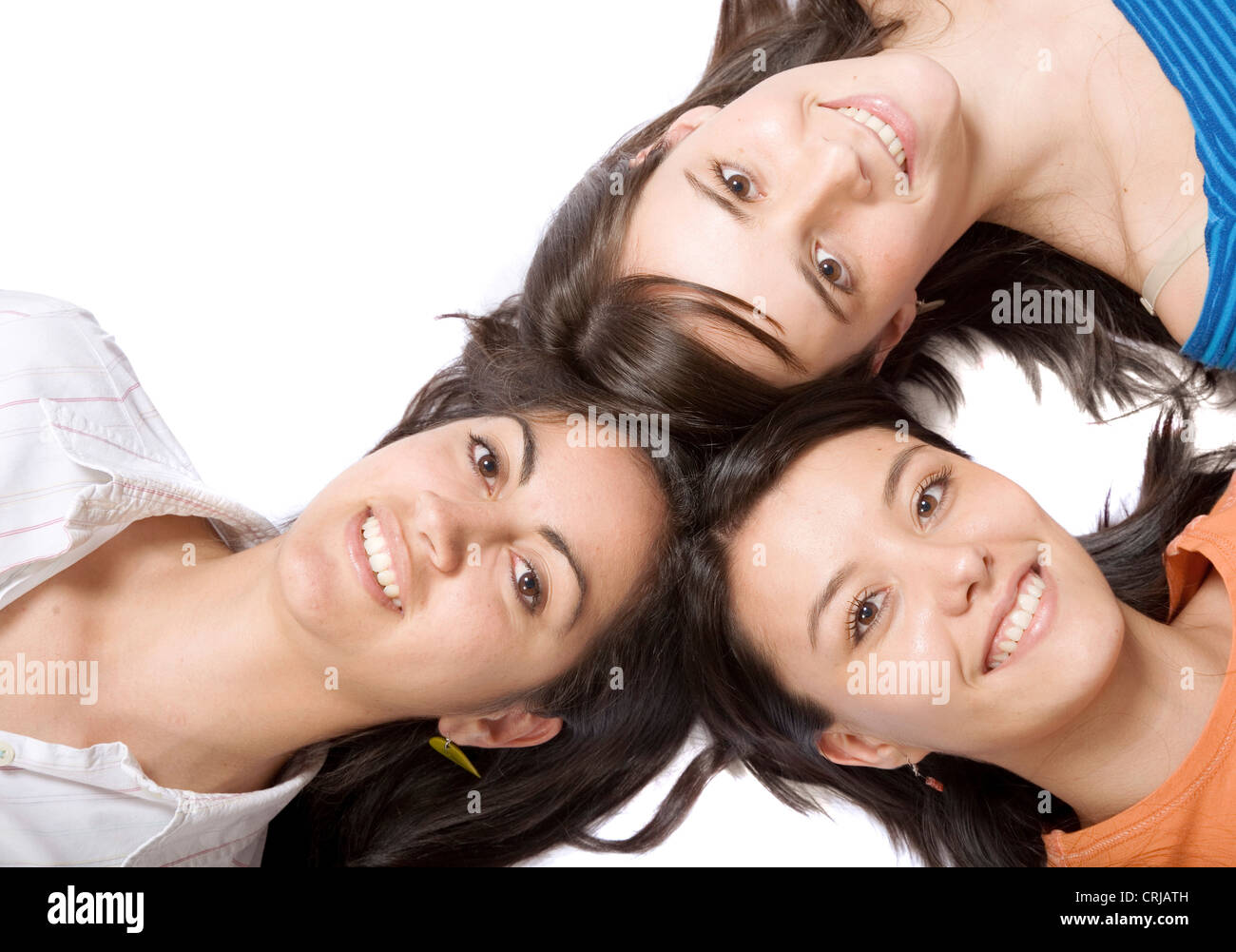 drei lächelnde junge Mädchen mit ähnlichen Haaren auf dem Rücken liegend mit dem Kopf zusammen Stockfoto