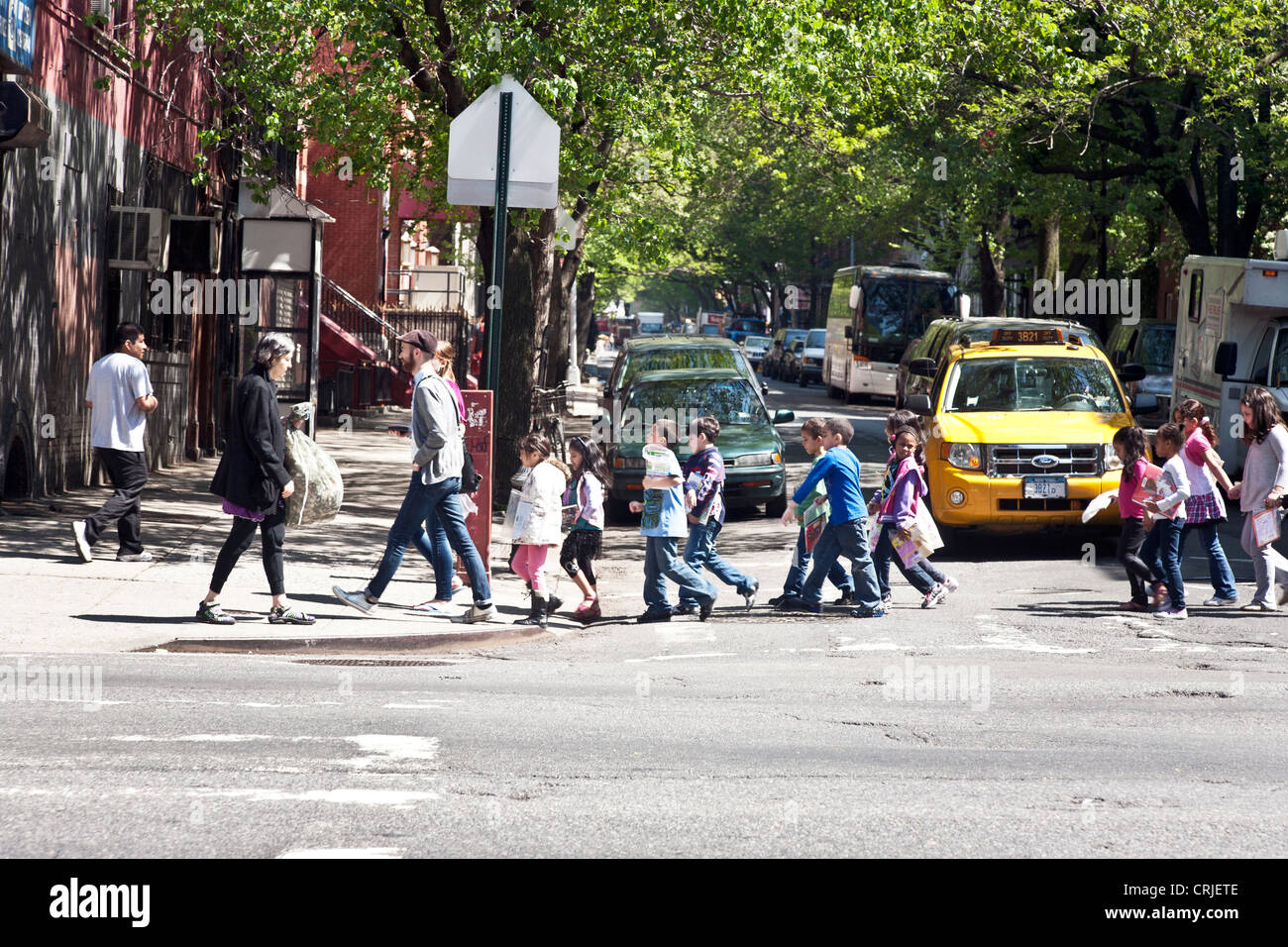 heterogene Gruppe von multiethnischen Grundschulkinder überqueren Sie die Kreuzung mit Lehrer & ältere Monitore auf West Side Manhattan Stockfoto