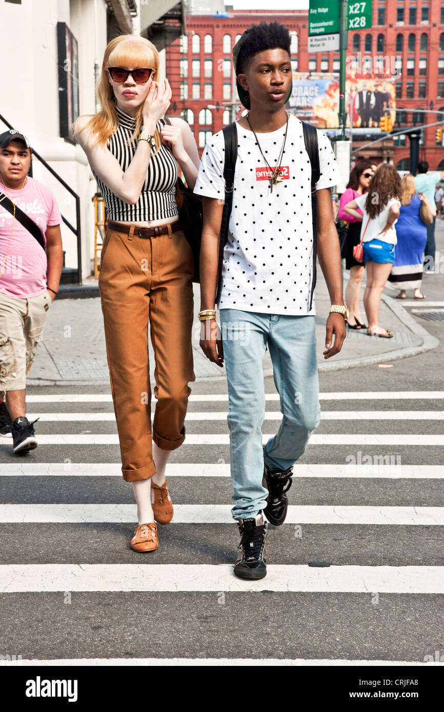 junger schwarzer Mann begleitet von hohen Albino Transvestiten Kreuzung Street in Soho-Viertel in New York City Stockfoto
