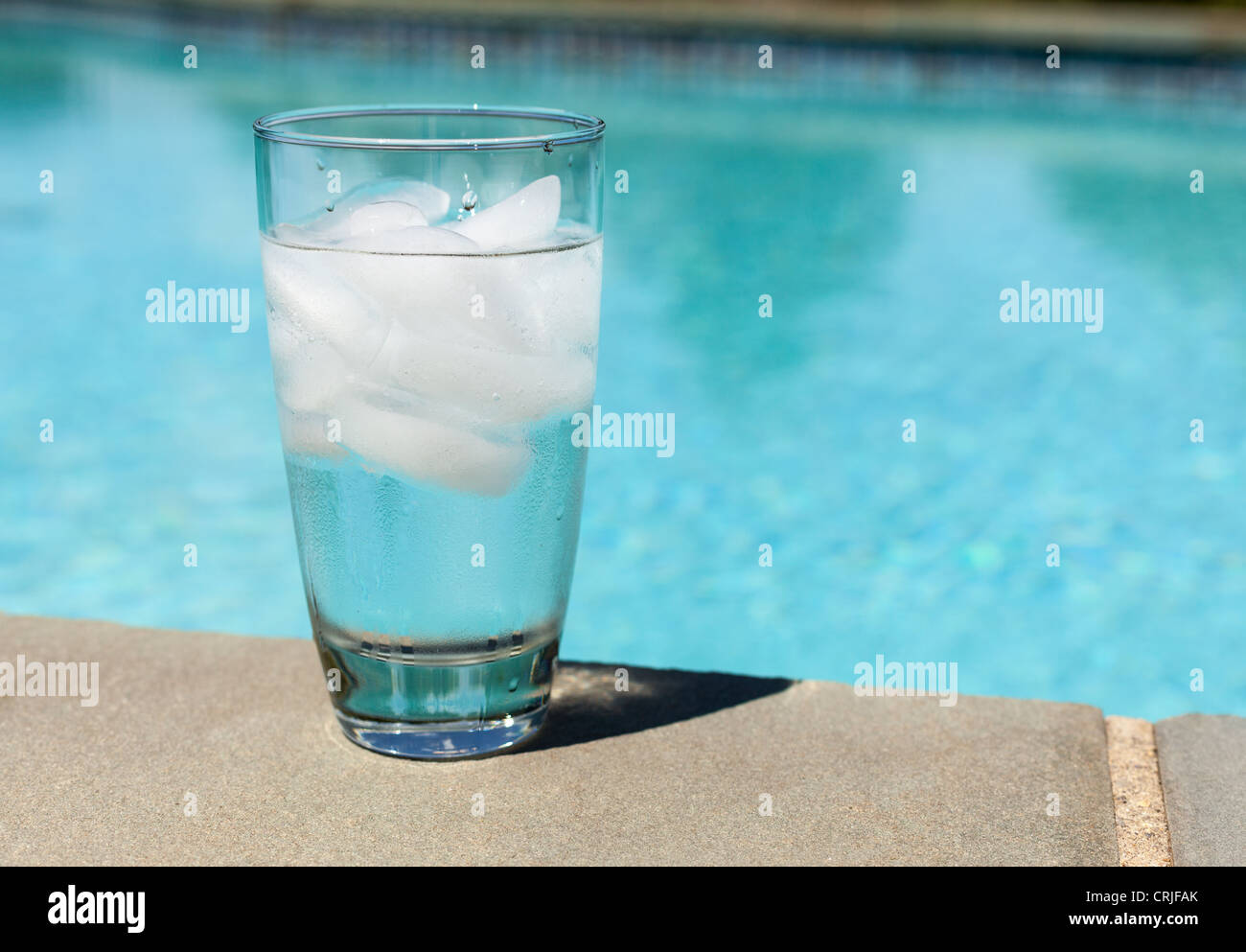 Klar Glas Wasser mit Eiswürfeln auf der blauen Swimmingpool Stockfoto