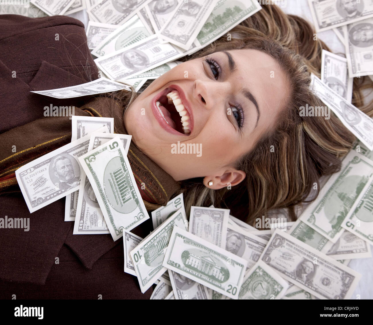 junge Frau Lachen mit dem Kopf auf Dollarnoten gebettet Stockfoto