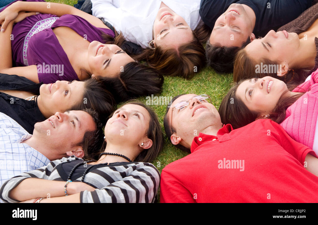 Freundeskreis glücklich lächelnd und entspannen im Freien mit Köpfe zusammen auf den Boden Stockfoto