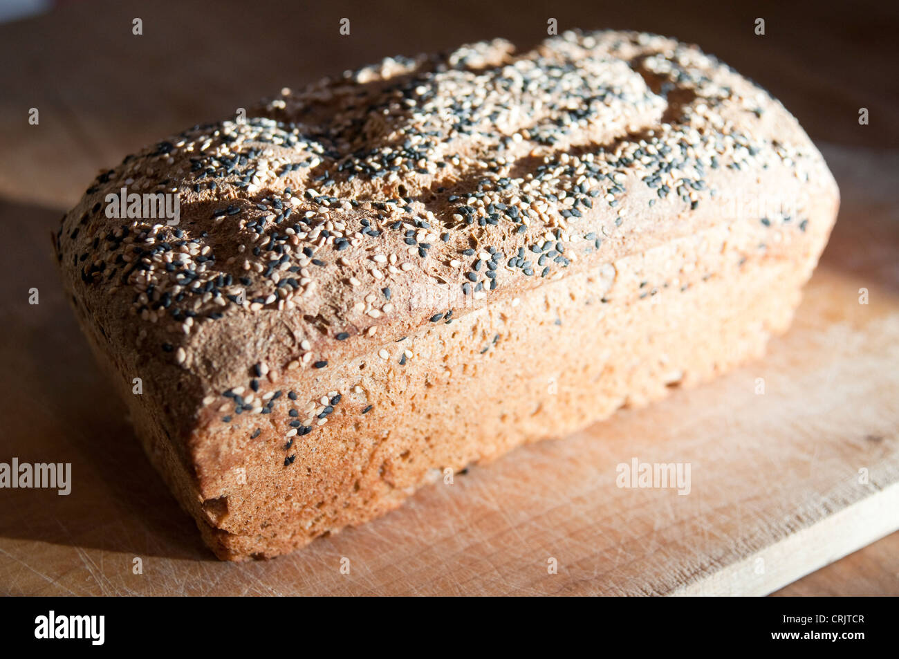 Frisch gebackene Brotlaib gesunde Brown auf einem hölzernen Brot-Brett im Sonnenlicht. Stockfoto