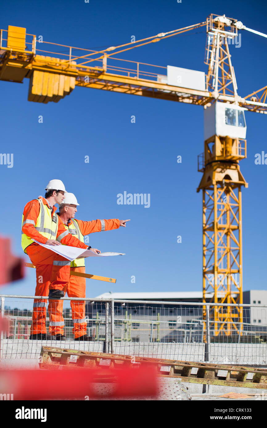 Arbeitnehmer, die Baupläne vor Ort lesen Stockfoto