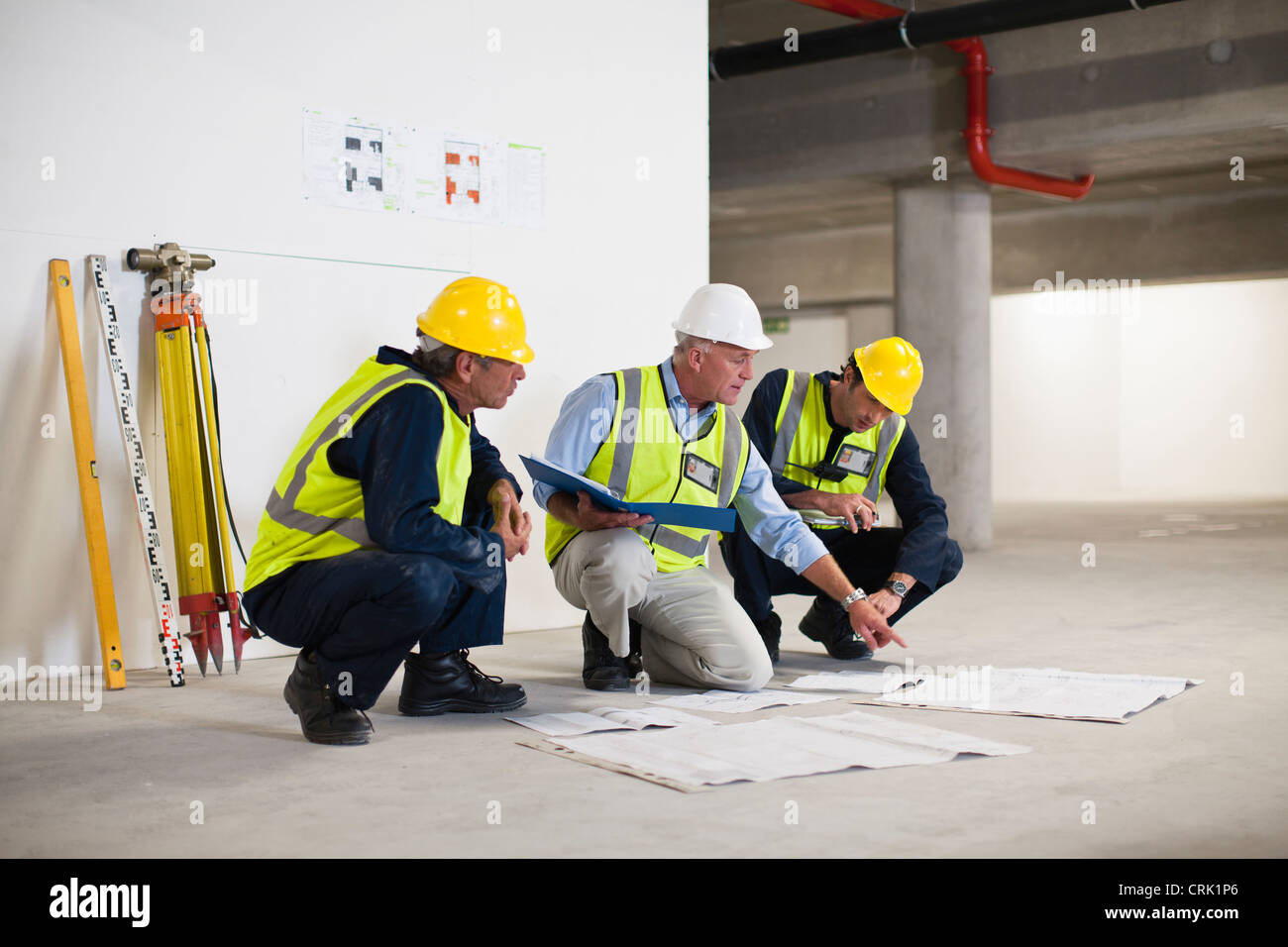 Arbeitnehmer, die Baupläne vor Ort lesen Stockfoto