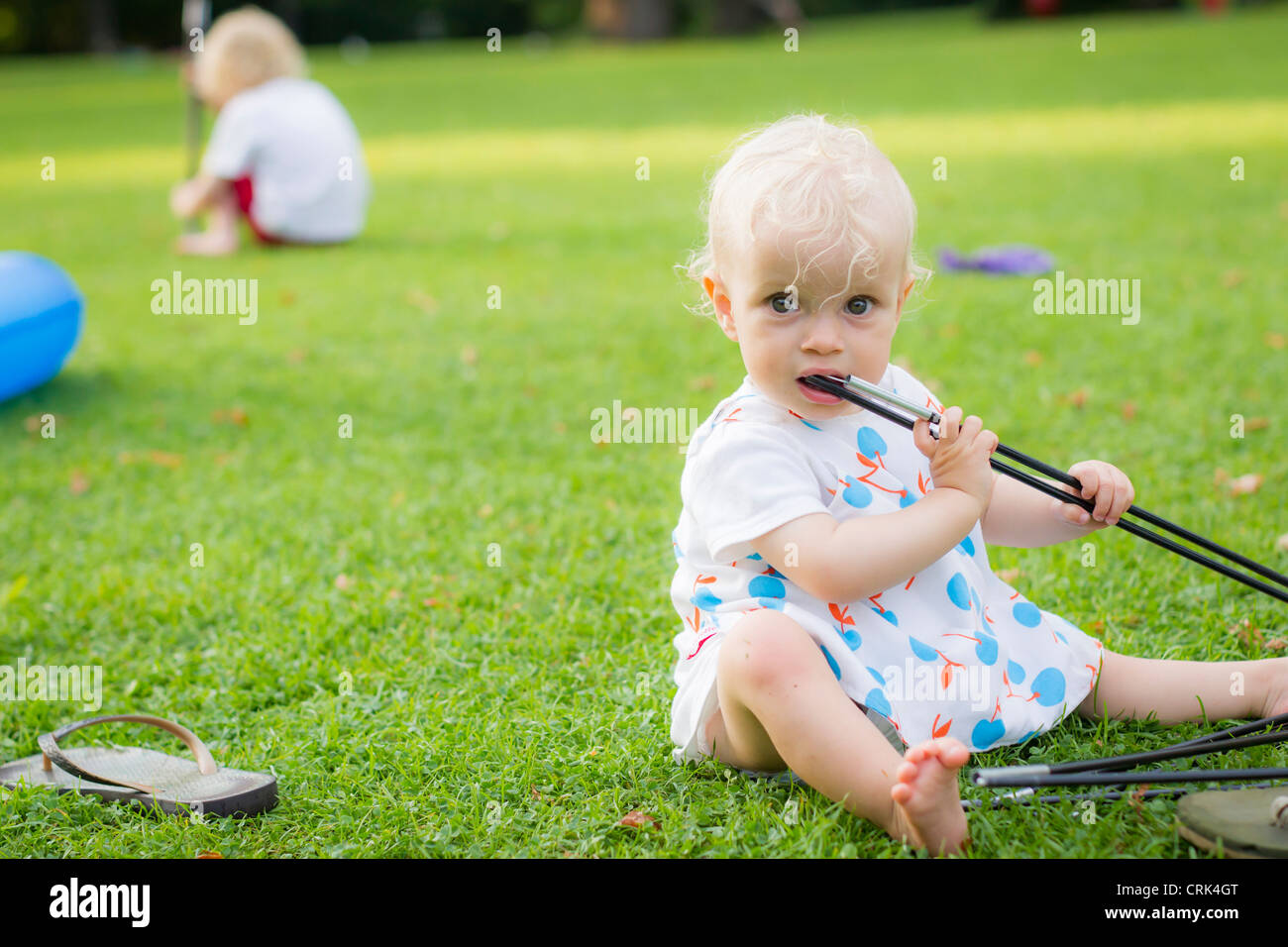 Babymädchen kauen auf Spielzeug im Garten Stockfoto