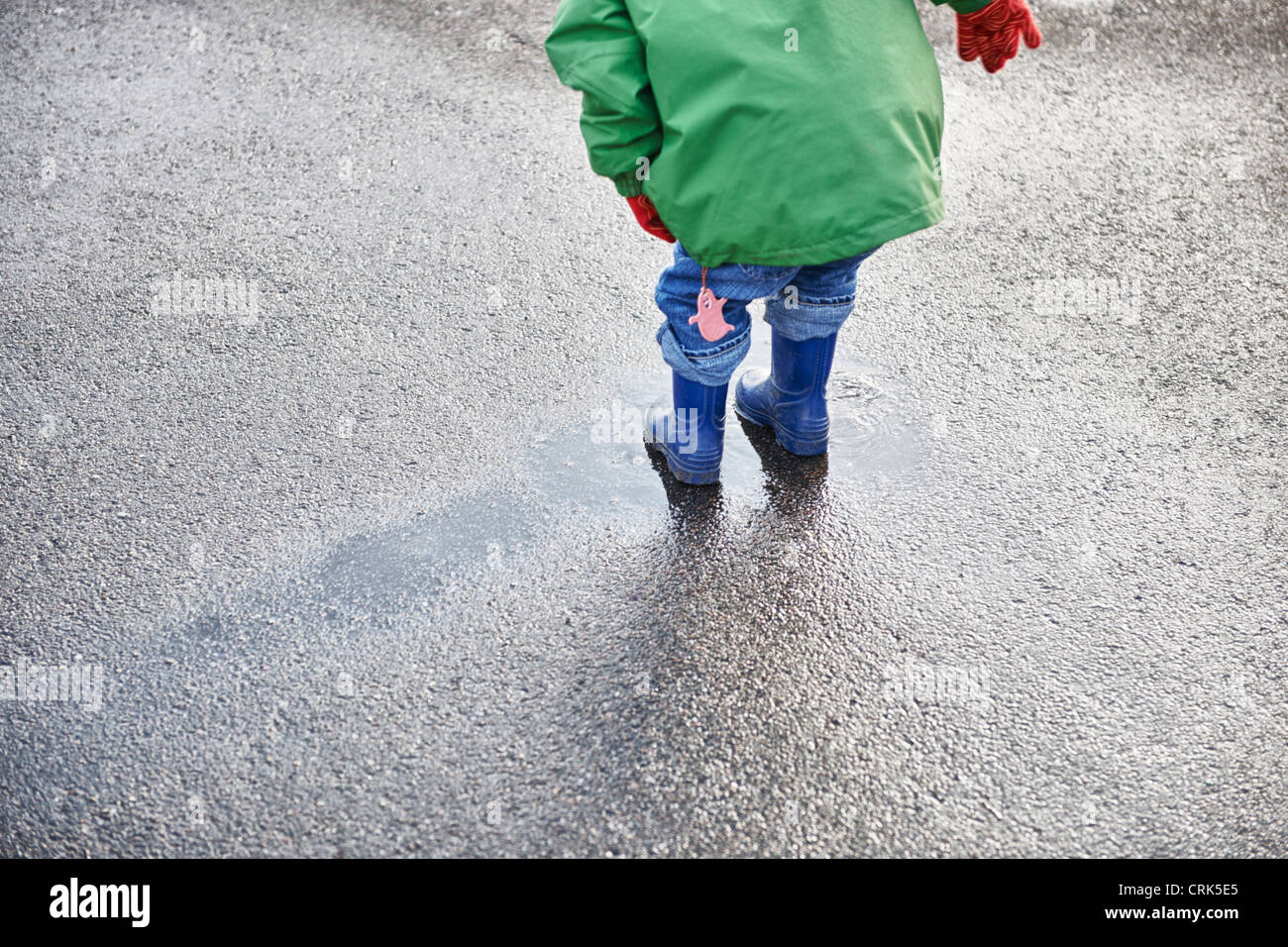 Junge im Regen Stiefel spielen in Pfütze Stockfoto