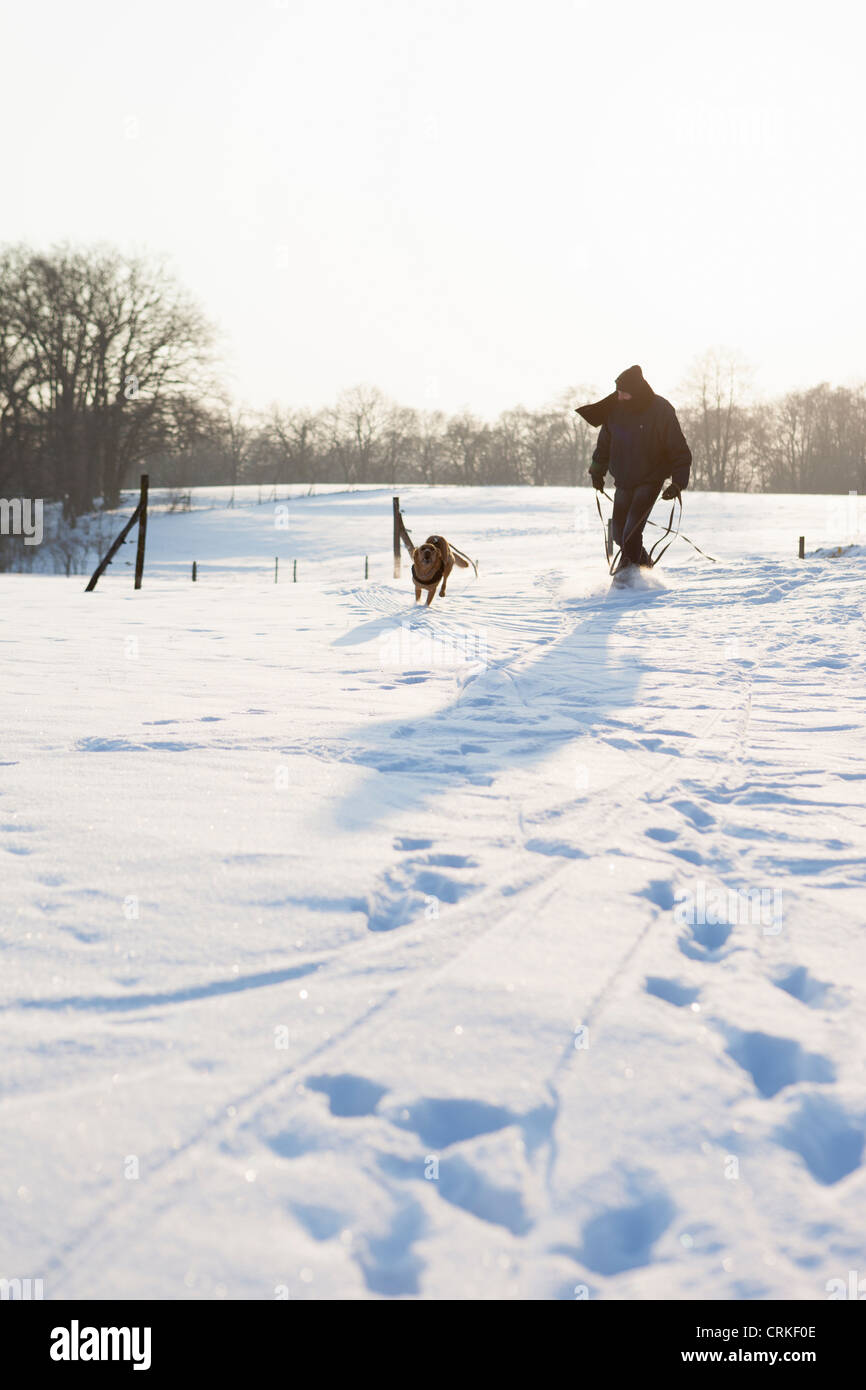 Mann zu Fuß Hund in schneebedecktes Feld Stockfoto