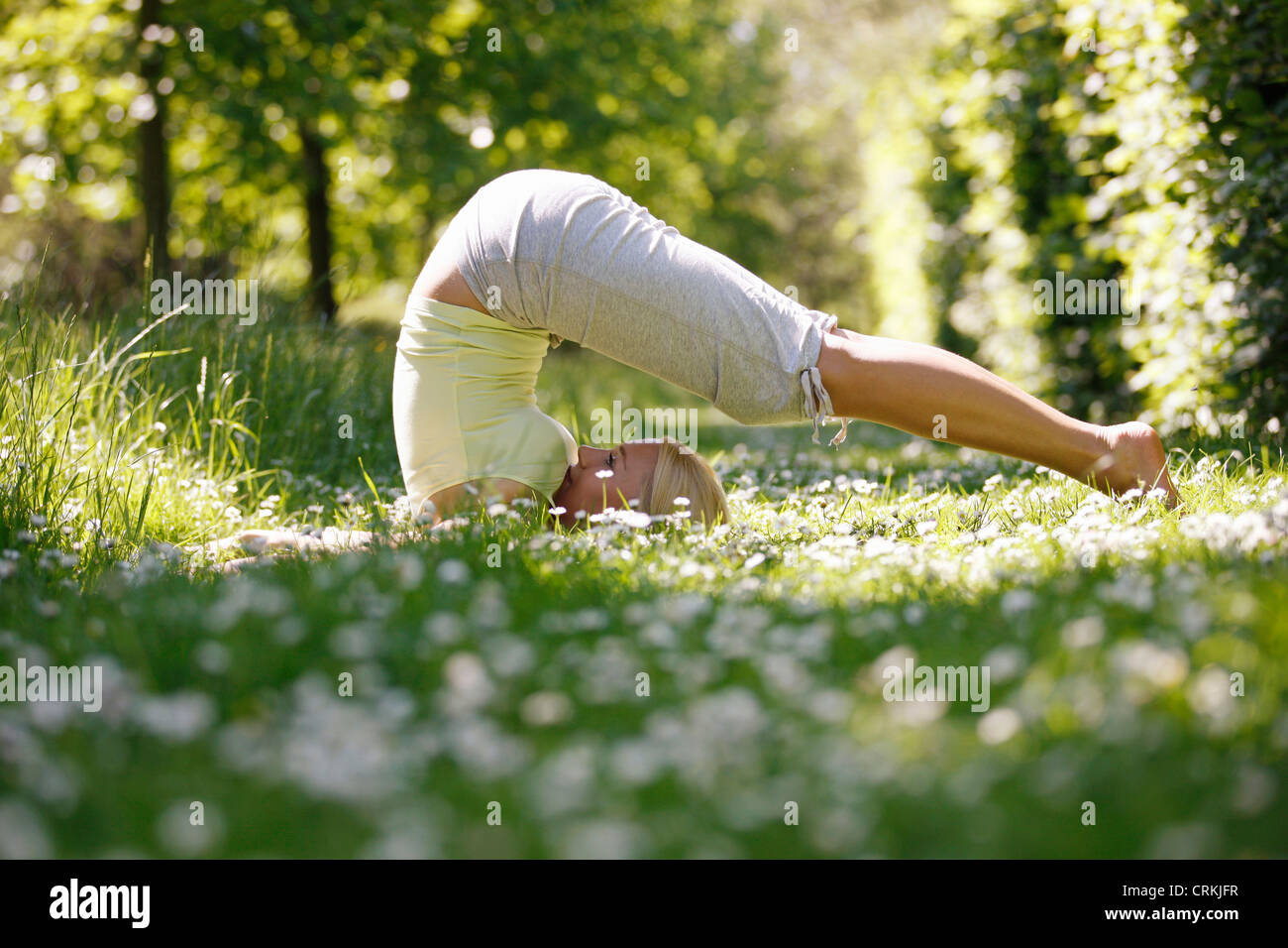 Eine junge Frau praktizieren Yoga außerhalb Pflug-pose Stockfoto