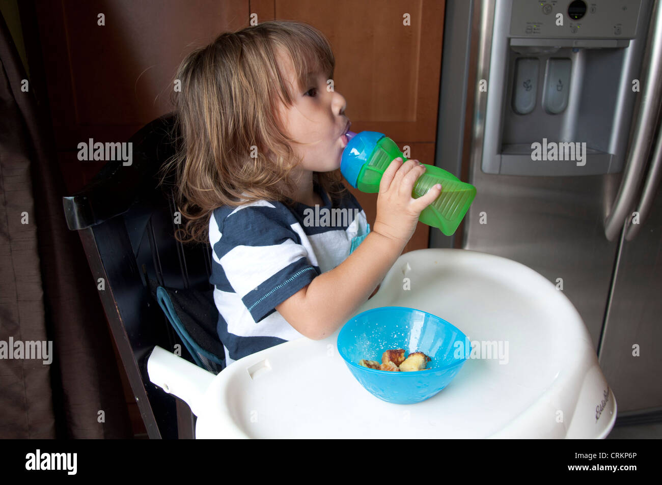 Niedliche Baby junge Kind im Hochstuhl trinken Stockfoto