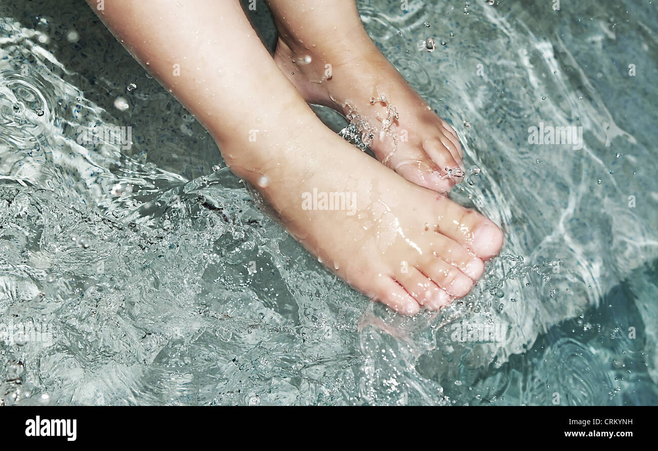 kleinen Jungen Füßen im Wasser plantschen Stockfoto