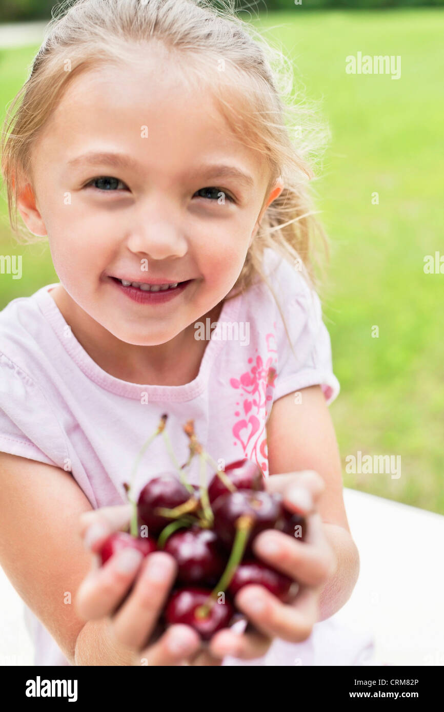 Porträt von ein fröhliches Mädchen mit Händen voll auf Bing Kirschen Stockfoto