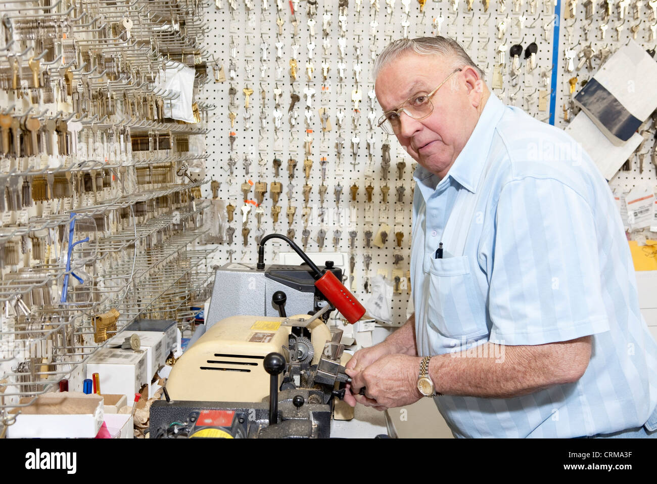 Senior Schlosser wegsehen und Schlüssel im store Stockfoto