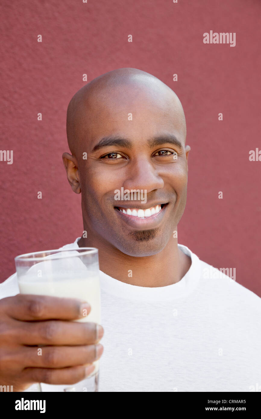 Porträt eines glücklichen jungen Mannes mit Milchglas auf farbigen Hintergrund Stockfoto