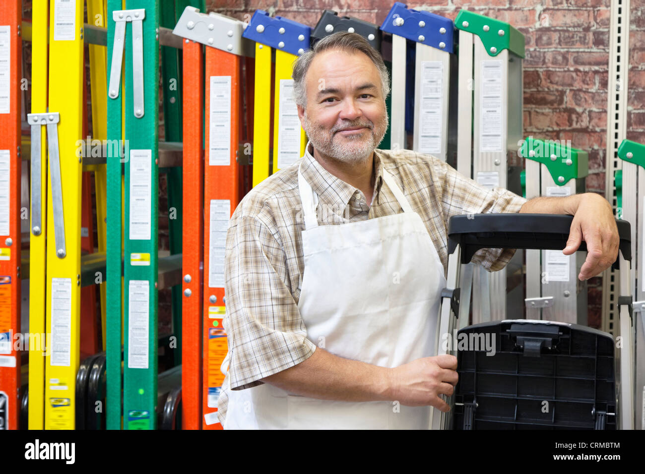 Porträt von glücklich Reife Verkäuferin stehen bunte Leitern im Hardware-Geschäft Stockfoto