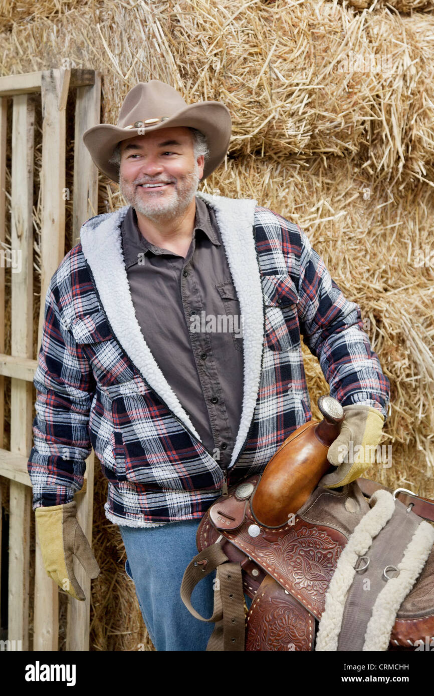 Glücklich Reife Cowboy Holding Sattel Stockfoto