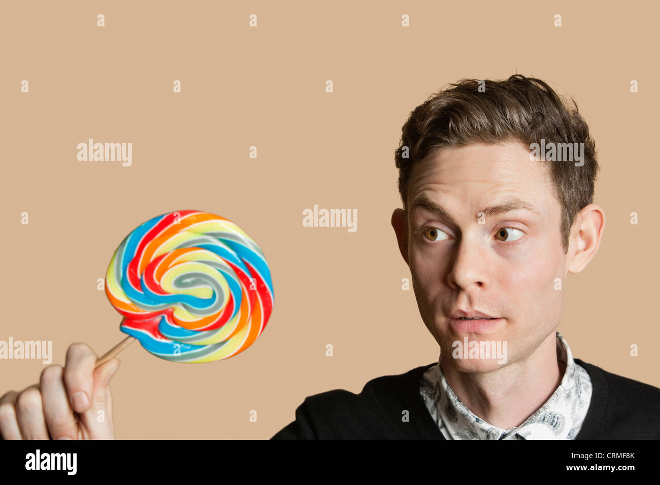 Mitte erwachsenen Mannes Blick auf Lollipop farbigen Hintergrund Stockfoto