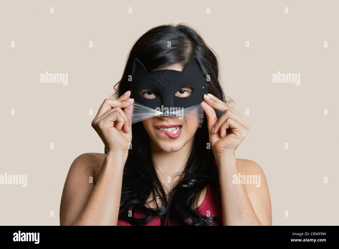 Porträt einer jungen Frau tragen Augenmaske beim beißen Lippe über farbigen Hintergrund Stockfoto