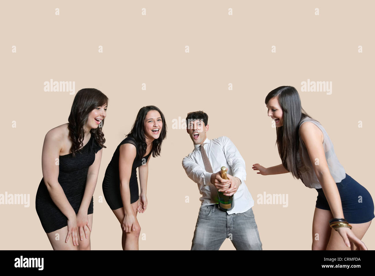 Junge Freunde öffnen, Flasche Champagner über farbigen Hintergrund Stockfoto