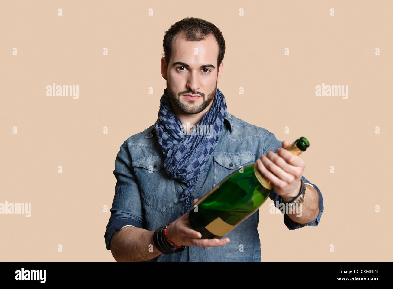 Porträt eines jungen Mannes mit Champagner-Flasche über farbigen Hintergrund zuversichtlich Stockfoto