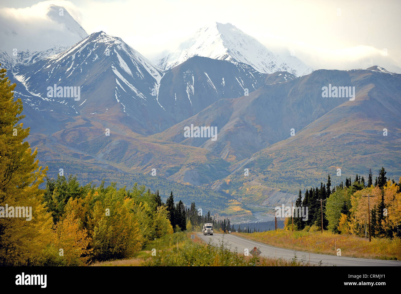 18 Wheeler oder LKW-fahren auf der Autobahn über schneebedeckte Berge und Herbst oder Herbst Farben im Yukon, Kanada Stockfoto