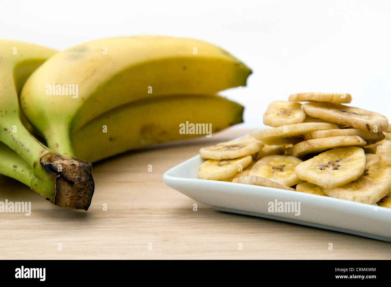 Getrocknete Bananenchips in kleinen weißen Schüssel auf Schneidbrett ...