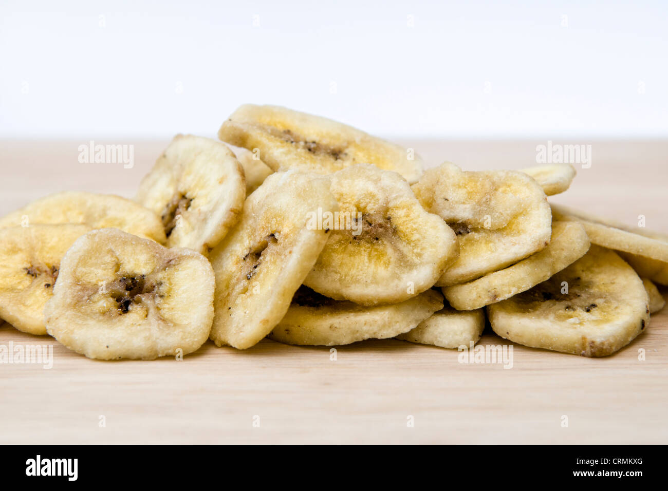 Getrocknete Bananenchips auf Schneidbrett aus Holz auf einem weißen Hintergrund Stockfoto